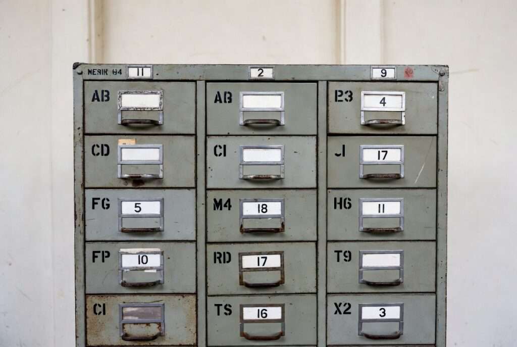 A rudimentary mechanical filing cabinet labeled in strict alphabetical order representing the flawed Pythagorean system.