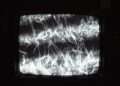 High contrast static noise on an analog screen representing the data paralysis and attention fracture caused by Uranus in Gemini.