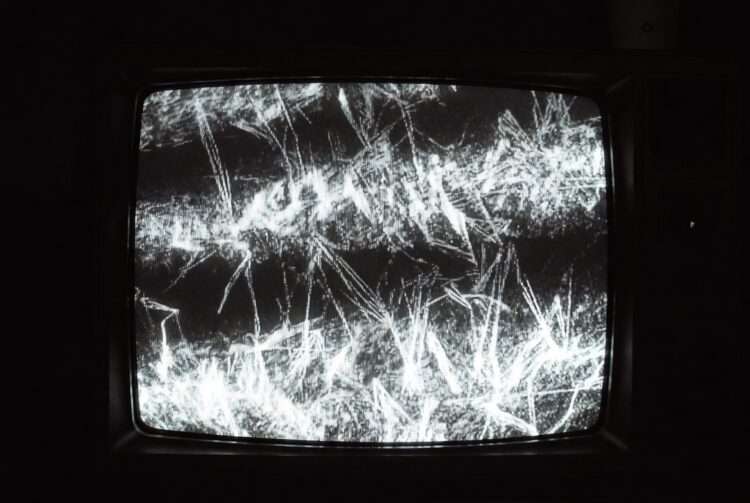 High contrast static noise on an analog screen representing the data paralysis and attention fracture caused by Uranus in Gemini.